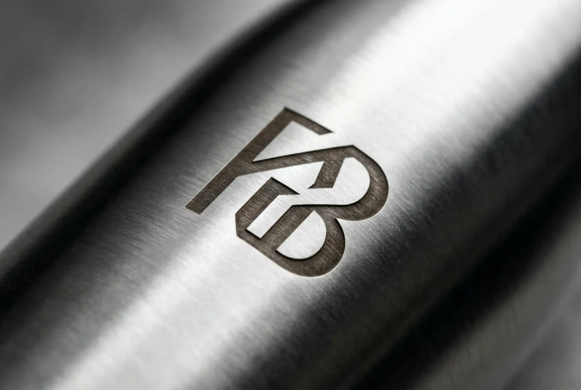 Gourde personnalisée entreprise : le guide complet 2026 3 Gros plan macro sur gravure laser d'un logo d'entreprise sur gourde inox brossée Balzeo, détail précision du marquage